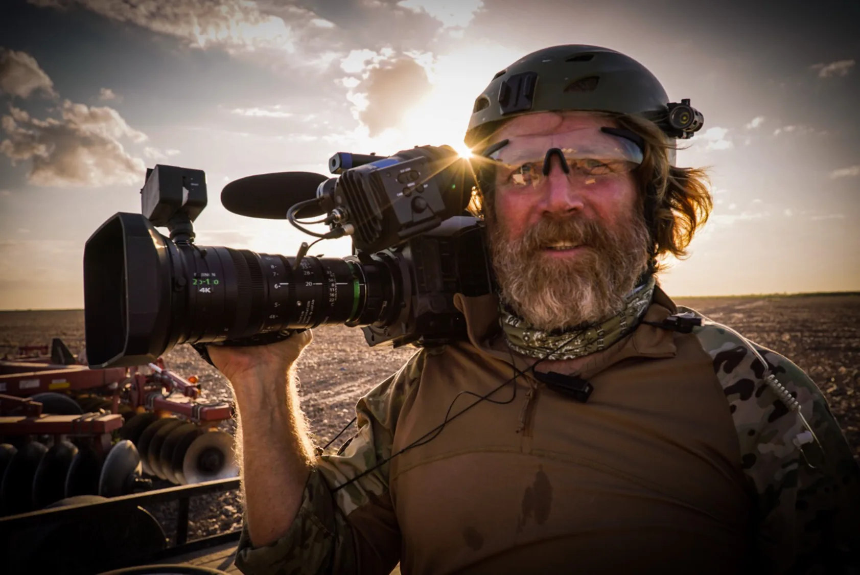 A bearded man holding a camera in the desert.